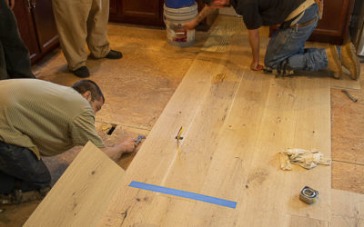 Worker installing 9" Live Sawn White Oak Flooring
